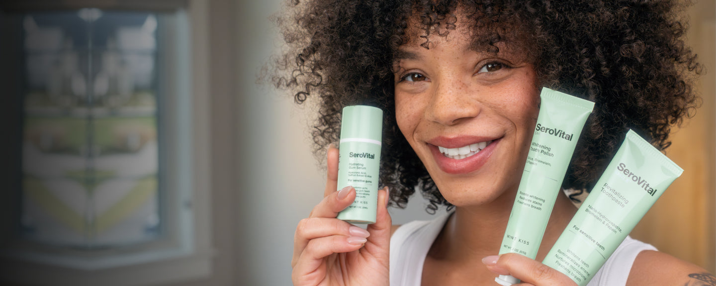 Woman holding SeroVital smile care products with a blurred background