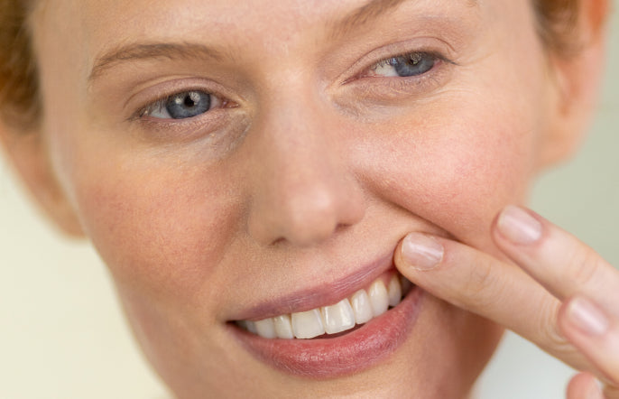 Woman with a finger on her cheek, close-up of face