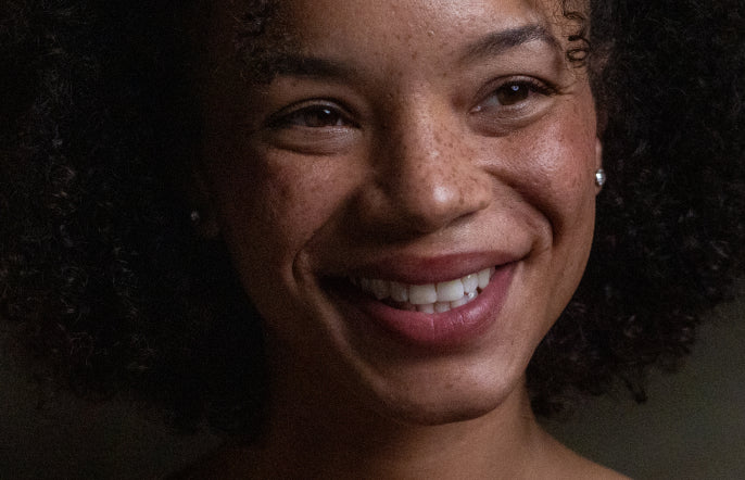 Close-up of a woman with a warm smile against a neutral background