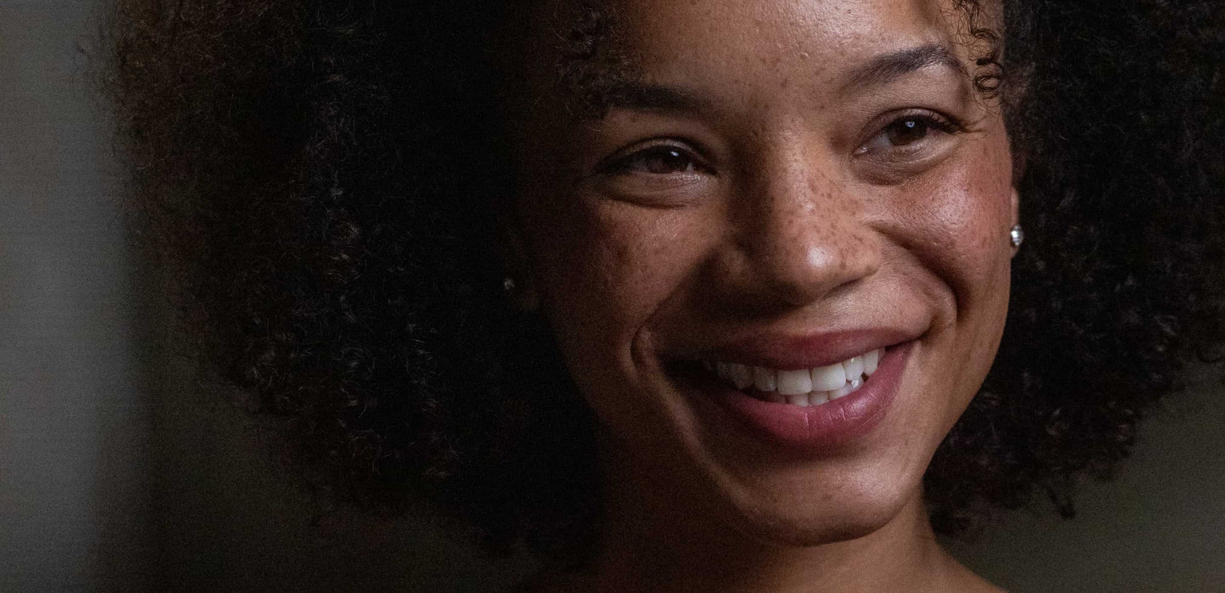 Close-up of a woman with a warm smile against a dark background