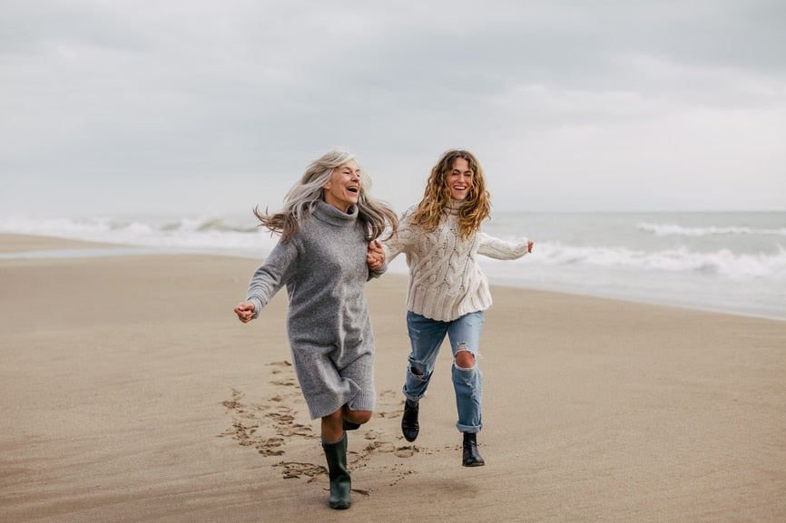 women laughing and running on the beach