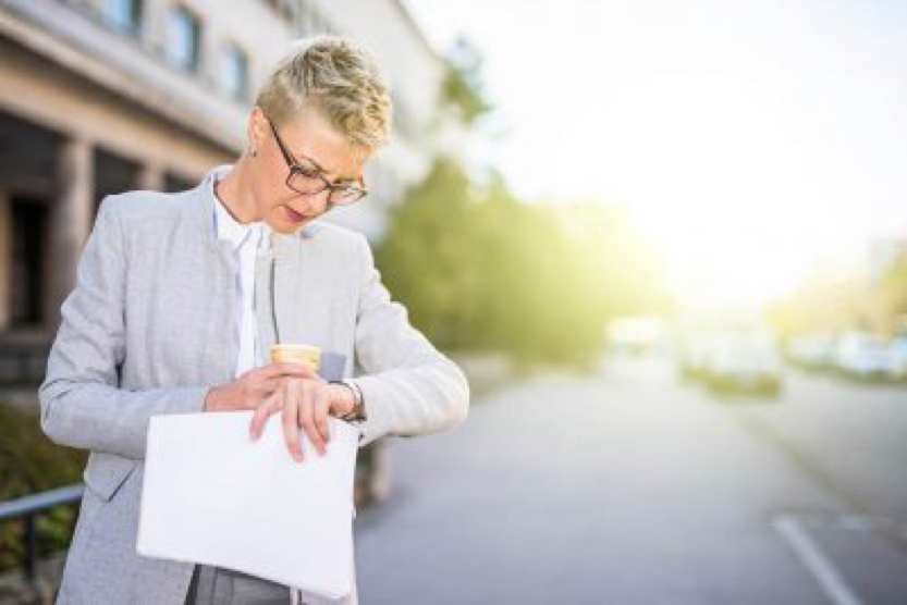 woman checking watch with coffee