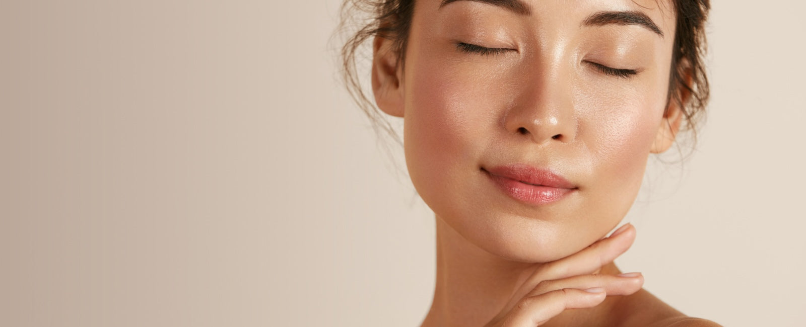 Woman with closed eyes and hand near face on a beige background