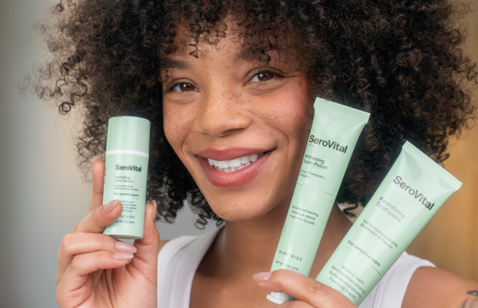 Woman holding three smile care products with a neutral background