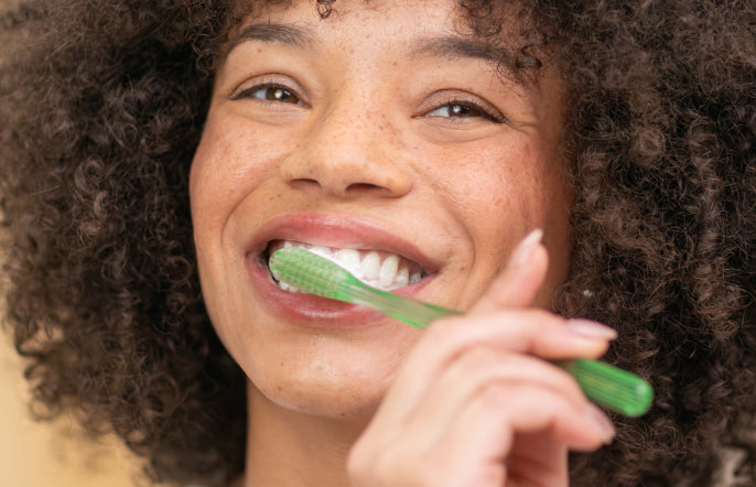 Woman brushing her teeth with a green toothbrush
