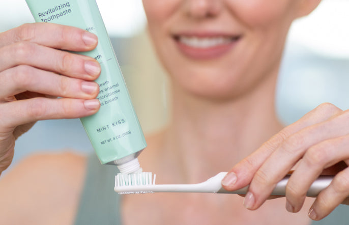 Person holding a tube of toothpaste and a toothbrush with a blurred background