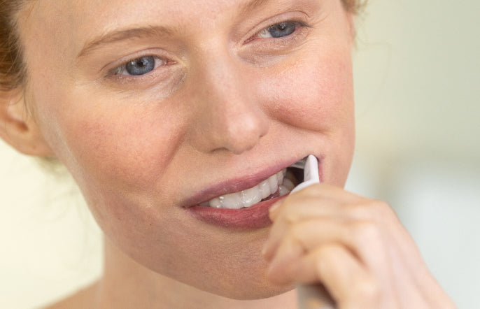 Woman brushing her teeth with a toothbrush.
