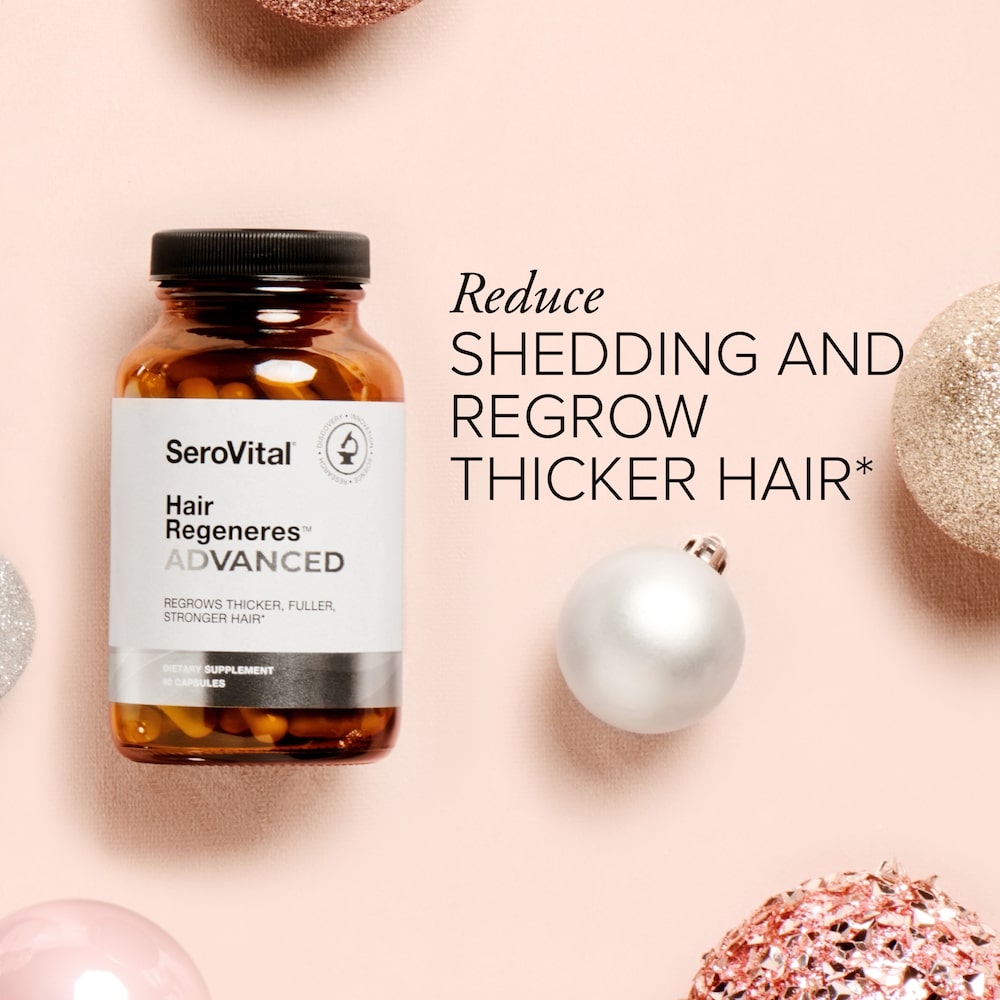 A glass bottle of hair supplement Hair Regeneres ADVANCED on a pink background with holiday ornaments and text that says Reduce shedding and regrow thicker hair