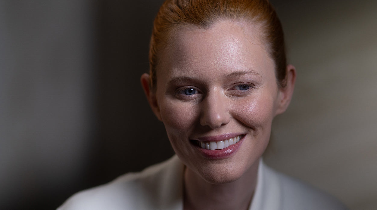 Woman with red hair smiling against a blurred background