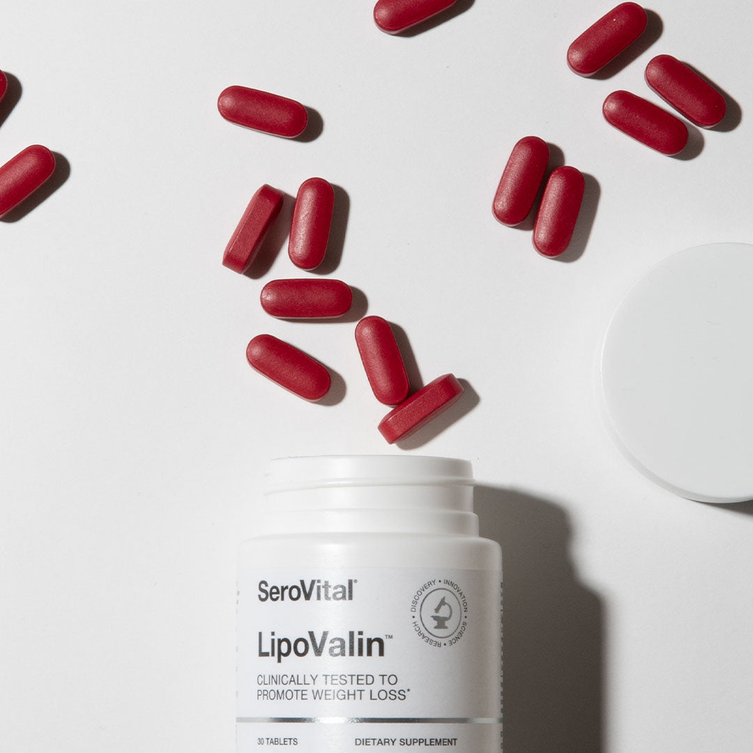 Red weight loss tablets spilling out of the top of the bottle