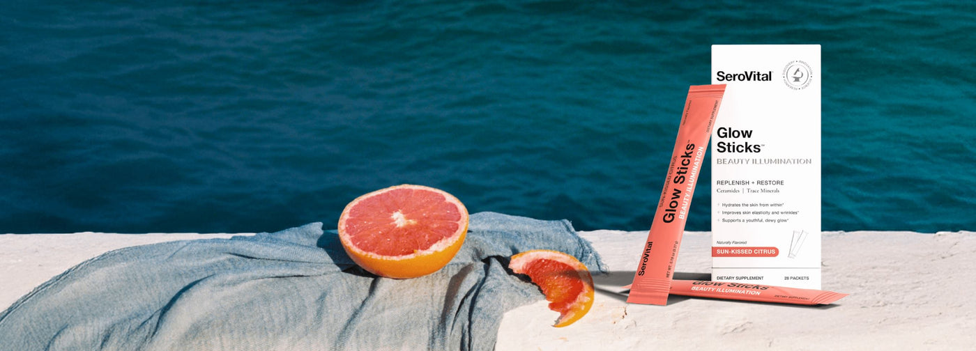 Glow sticks and packaging on a towel with a Citrus fruit, against a blue water background