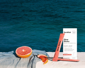 Glow sticks and packaging on a towel with a Citrus fruit, against a blue water background