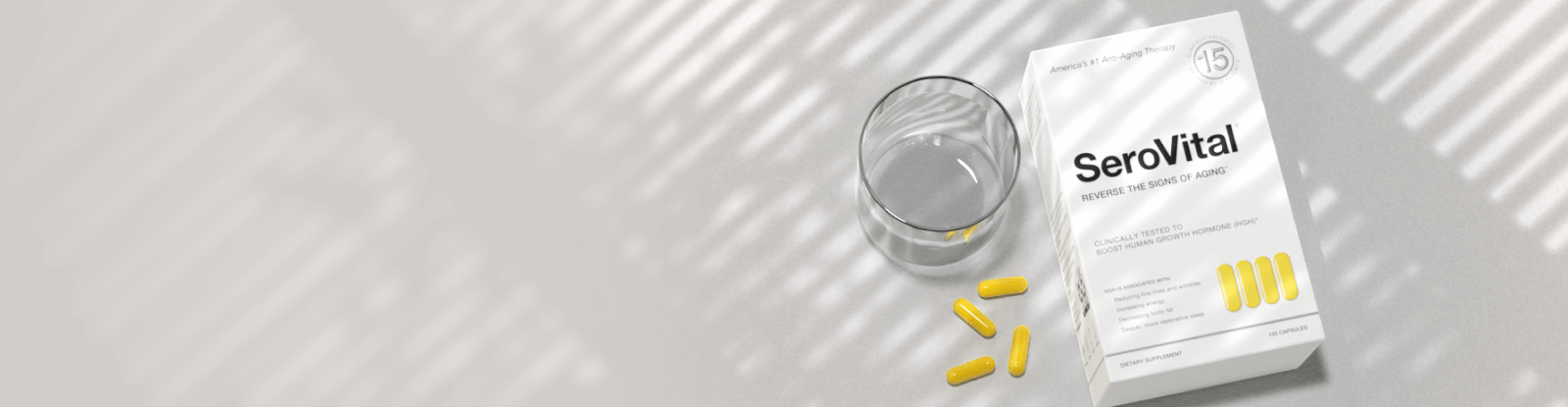 White box of SeroVital anti-aging supplement with yellow capsules and a glass of water.