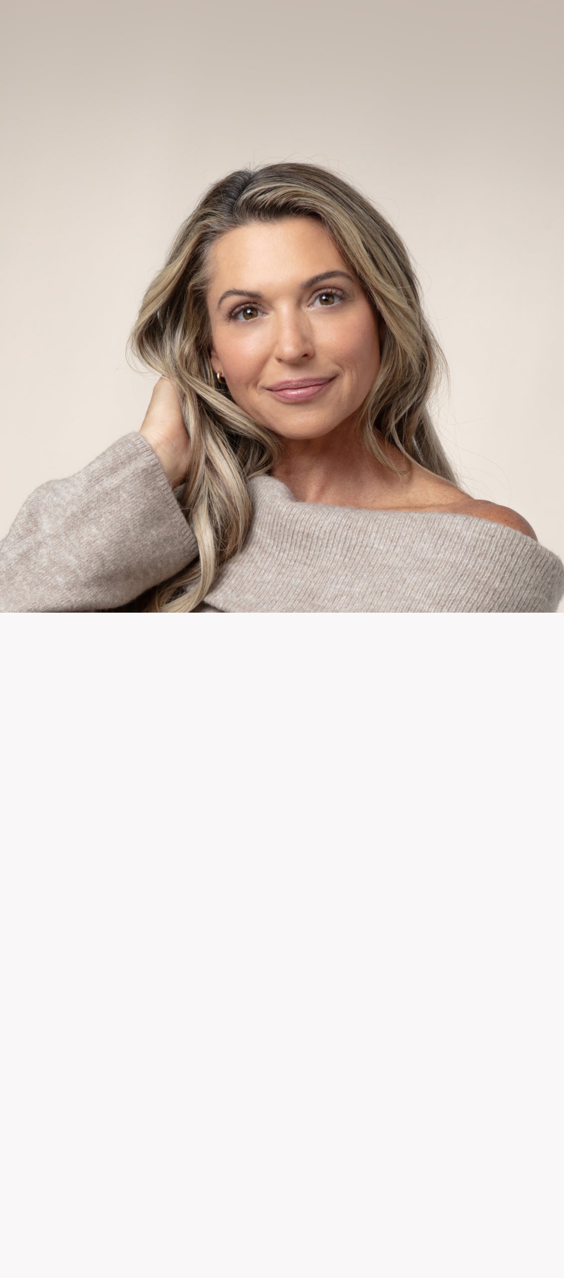 Woman with blonde highlights wearing a beige off the shoulder sweater