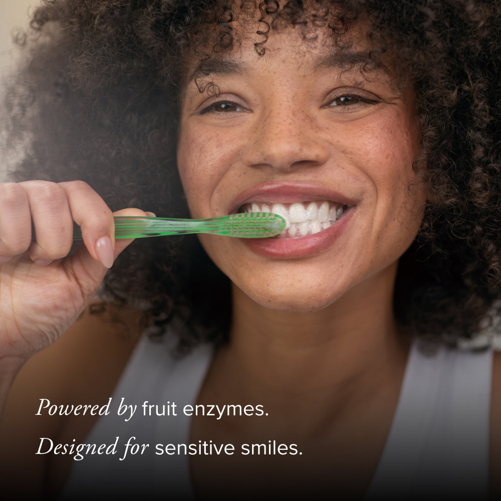 Woman brushing her teeth with a green toothbrush, text about fruit enzymes and sensitive smiles.