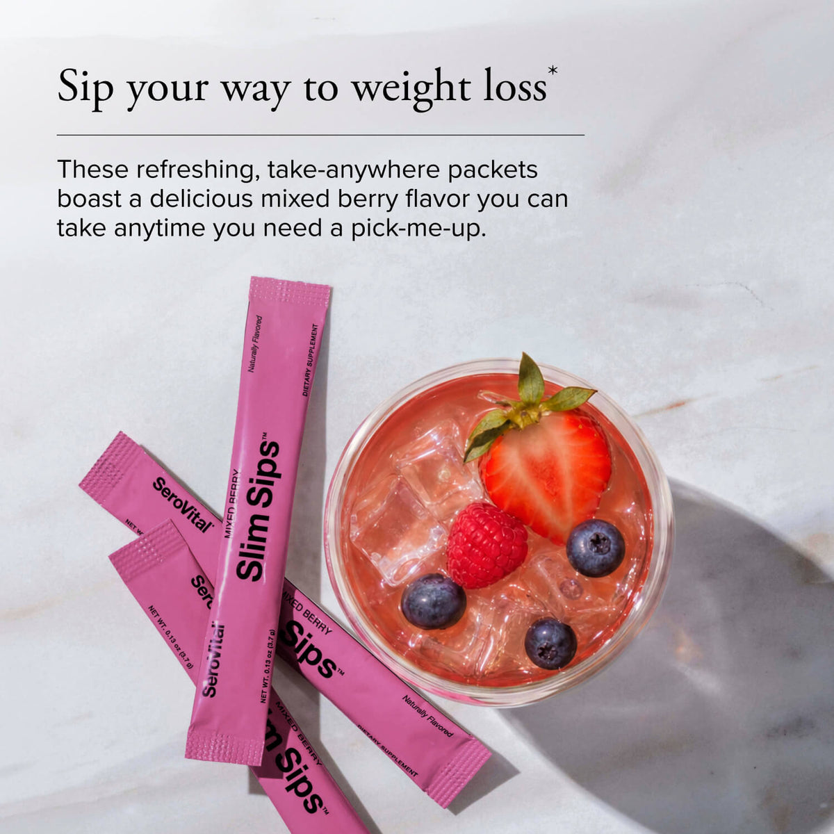 Pink Slim Sips weight loss packets arranged on a light marble surface next to a glass of pink iced drink with strawberries and blueberries. Text at the top reads 'Sip your way to weight loss'.