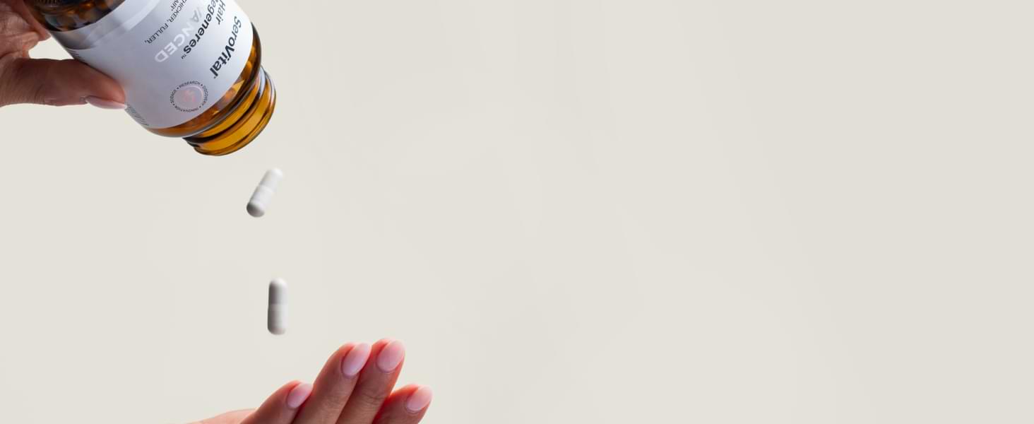 Hand pouring pills from a bottle onto a light surface