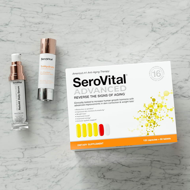 A tube of hyaluronic acid serum TriHydrate, retinoid serum RetinAll, and beauty boosting SeroVital ADVANCED lying on a marbled background