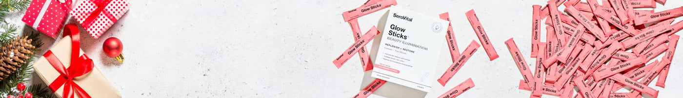 Serovital Glow Sticks Beauty Illumination box and individual packets on a white, holiday-themed background with red and white wrapped Christmas gifts and evergreen decor. A perfect holiday gift idea.