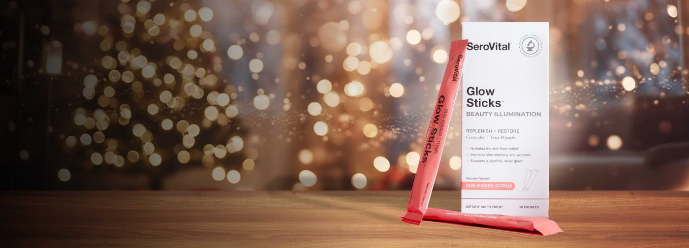 SeroVital Glow Sticks Beauty Illumination supplement box and single packet on a holiday-lit wooden surface.
