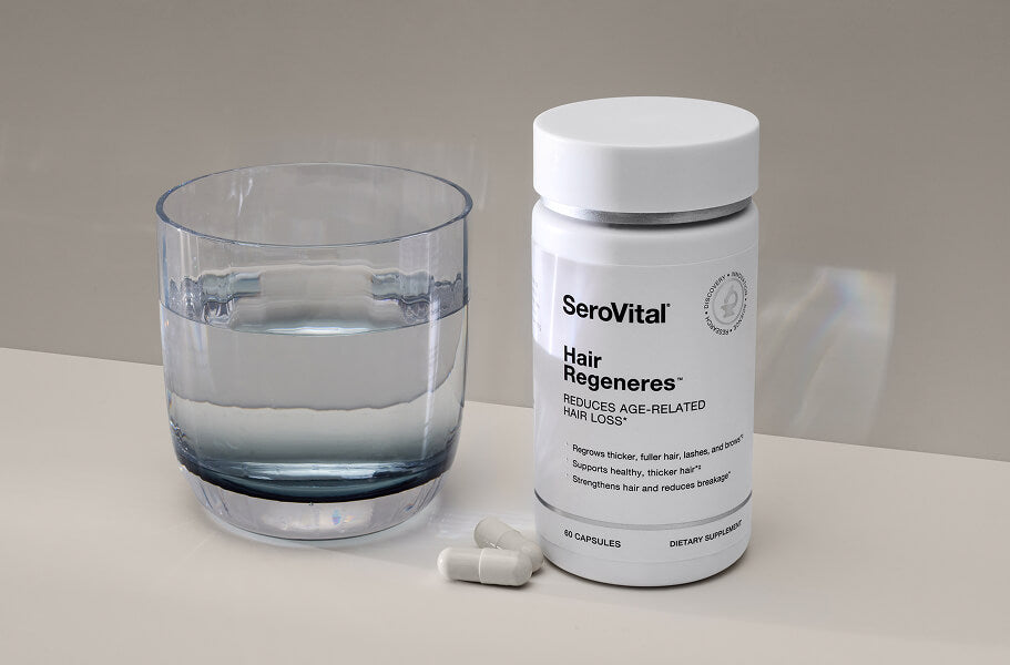 SeroVital Hair Regeneres supplement bottle with a glass of water and capsules on a neutral background