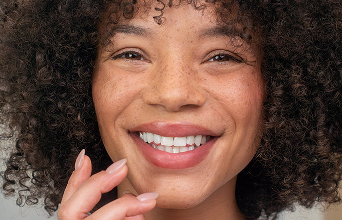 Close-up of a person with curly hair smiling