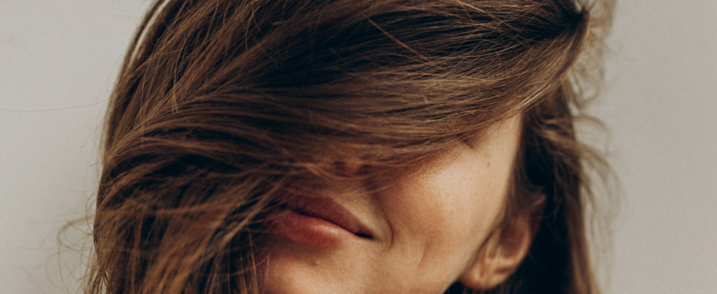 Close-up of a person with windblown hair against a neutral background